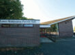 Brick building labelled Lower Withington Parish Hall with a sloping roof and large windows.