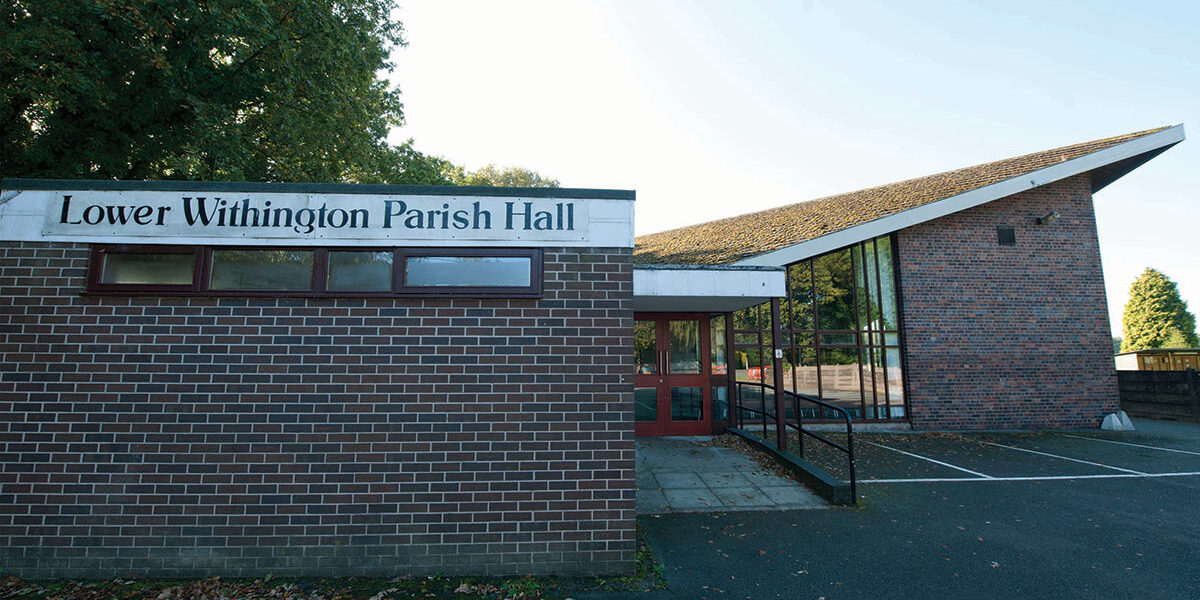 Autumn7 Brick building labelled Lower Withington Parish Hall with a sloping roof and large windows.