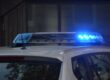 Blue police lights flashing on top of a white vehicle, seen from behind.