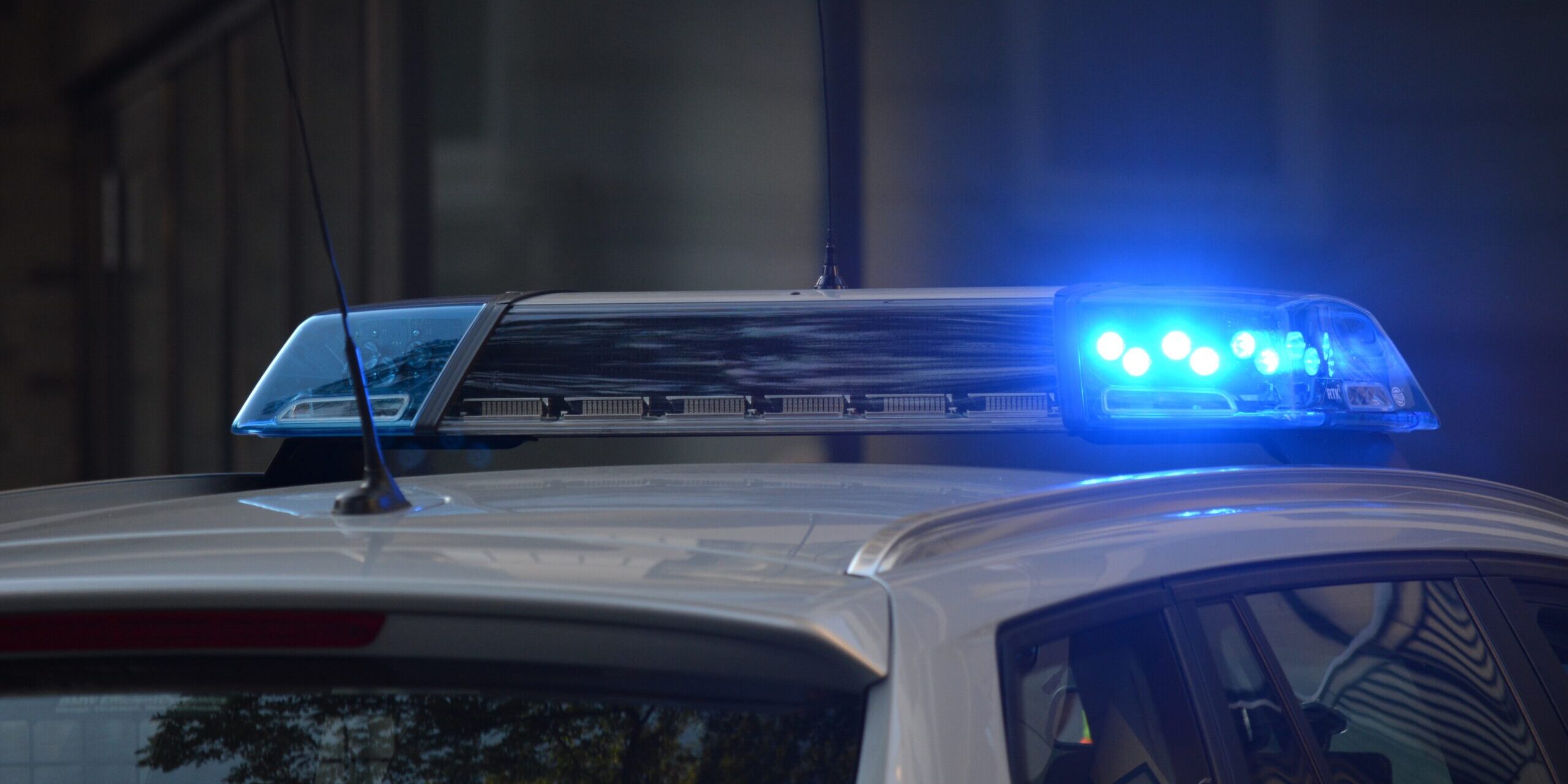 Blue police lights flashing on top of a white vehicle, seen from behind.